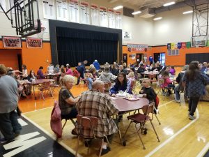 Students are shown having a gravy breakfast with their grandparents in the gymnasium at Lynn Camp Elementary School