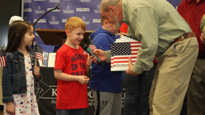 Dr. Ashburn is shown presenting an American Flag coloring book to a student.