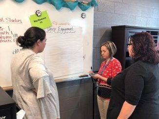 Shown are three teachers participating in a carousel activity as they visited each key resource and defined characteristics of it on a poster.