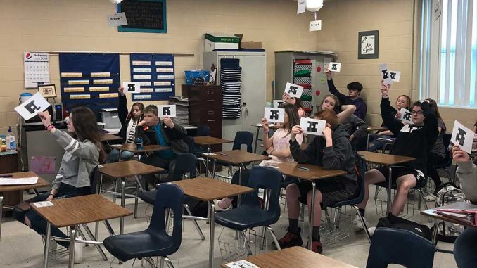 Students hold up papers, no technology needed, to use Plicker technology to report their response.