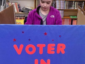 Voter in session booth at Lay Elementary 4th grade election. A student is shown casting their vote.