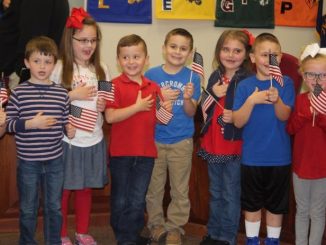 Students are shown leading the Pledge of Allegiance at the March 2019 board meeting.
