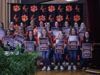Softball players at Lynn Camp pose in front of the LC backdrop during the November Board meeting.