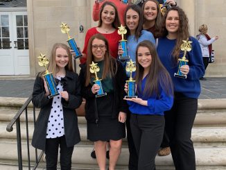 DECA students are shown outside a building at EKU holding their trophies from the regional competition.