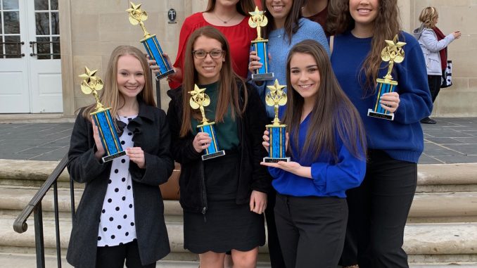 DECA students are shown outside a building at EKU holding their trophies from the regional competition.