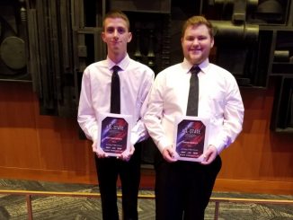 Two male choir students hold their award plaques