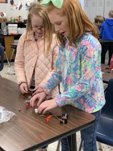 Two female students test circuits using batteries.