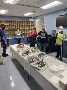 Staff members are shown in the work room at Knox Central with a dessert table in the center.
