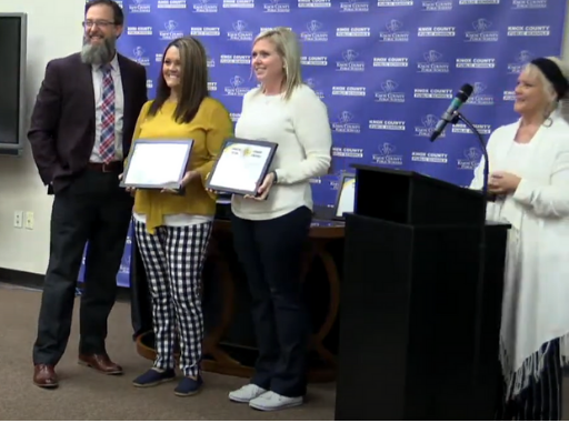 Superintendent Ledford is shown presenting an award to two teachers during the Board meeting.