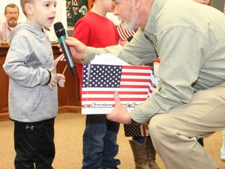 Dr. Ashburn presenting a young student with an American flag award for leading the Pledge of Allegiance.