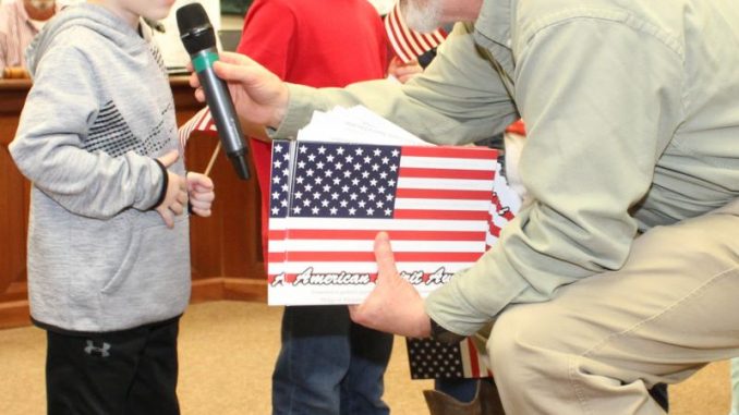 Dr. Ashburn presenting a young student with an American flag award for leading the Pledge of Allegiance.