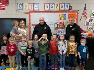 School resource officers are shown with students in an elementary classroom standing.