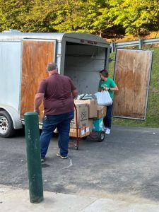 Individuals are shown unloading books from a trailer.